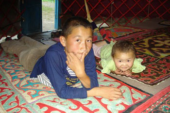 The wide eyed children on the colourful felt rugs of the yurt