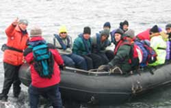 A Zodiac boat filled with eager explorers is pulled up onto the beach of Deception Island.