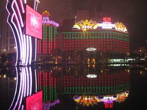 The Wynn Casino and the Hotel Lisboa Casino garishly lighted at night and reflected in the fountain.