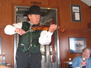 A fiddler performs on the GraWandering minstrels entertain the passengers. Don’t forget to tip!