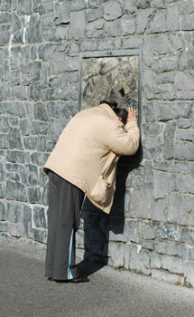 A pilgrim prays at a section of stones graced by the Virgin Mary at Knock.