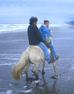 Anna and Nelson riding horseback on the beach in Chiloe, Chile