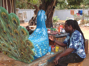 Coffin craftsman putting finishing touches on a peacock coffin.