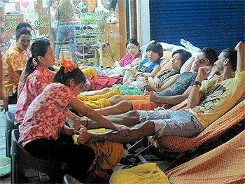 A group of people take a break and get a foot massage while the craziness of the Songkran Festival goes on around them.