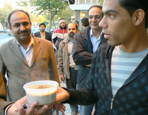Men waiting in line for porridge on a Shiraz street.