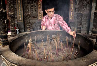 Man lighting incense at the Tienhou Temple