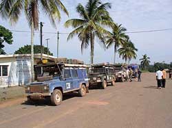 Arriving in Bakoumba, Gabon. Our ‘overland’ vehicles lined up along the main street as we search for the immigration official and enjoy cool drinks purchased from a local vendor.
