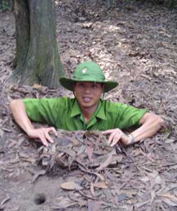 A tour guide shows visitors one of the tunnels used by the Viet Cong.