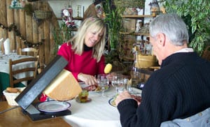 A couple enjoys a lunch of Raclette, melted cheese that is scraped off a wedge as it’s heated in a special grill. 