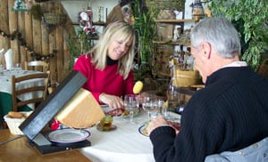 The French Alps: Snowplowing My Way Through 1 A couple enjoys a lunch of Raclette, melted cheese that is scraped off a wedge as it’s heated in a special grill.
