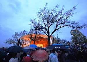 The crowd seeks cover under their umbrellas. 