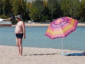 Vacationers sunbathe standing up on the beach at Issyk Kul.