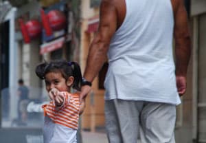 Little girl waving to a street vendor on the walking street (peatonal) Sarandi