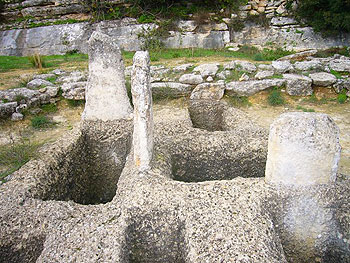 The Phourni Cemetery in Crete 3 Shaft graves and stelae of the Mycenean Grave Enclousure. You can see the remains of the enclousure wall behind the graves.