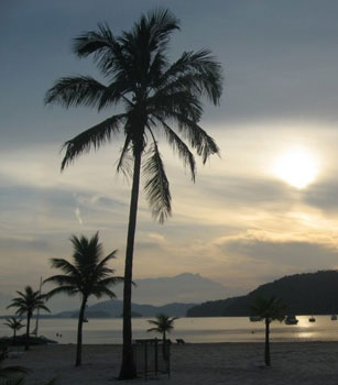 Sunrise over the beach and bay of Hotel Do Frade with the surrounding mountains blue in the morning light.