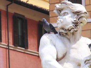A pigeon perches on a satyr.