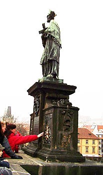 A Whirlwind Tour of Prague 6 A visitor touches the plaque on the right beneath St. John of Nepomuk's statue.