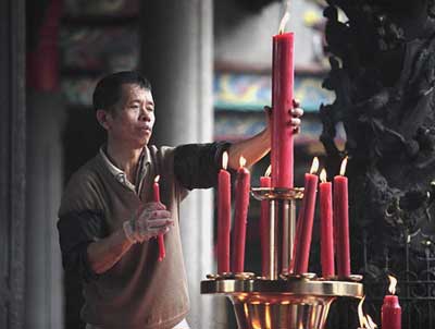 A man lights prayer candles at the Tienhou Temple in Tainan.