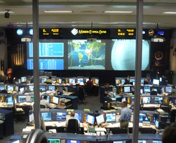 Mission Control at the Johnson Space Center in Houston. The curved lines on the screen track the orbits of the Space Shuttle.