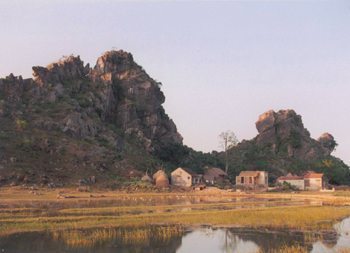 A typical scene outside Van Long Nature Preserve, not far from Cuc Phuong. The landscape is dominated by the huge, weirdly shaped, eroded limestone hills. Like many homes in the area, the house in the foreground has a fish pond in its front yard. Photo by Dan Drollette