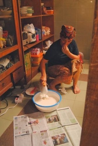 Ibu Dar preparing handmade butter in her rustic kitchen