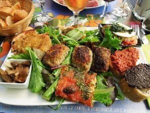 Assiette Provençal (Clockwise from Top Left: Pissaladière, Salade Niçoise, Pâté à Tartiner over bread, Pizza, and Marinated Mushrooms. Center: Farcis Niçois). photos by Derek Noll.