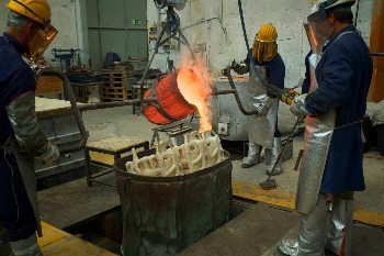 A precision team of foundry workers pour molten bronze into a form that is part of a large Botero sculpture. Photos by John Keahey