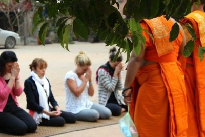 Cartagena: A Fitness Escape 3 Participants kneel before monks in Cambodia.