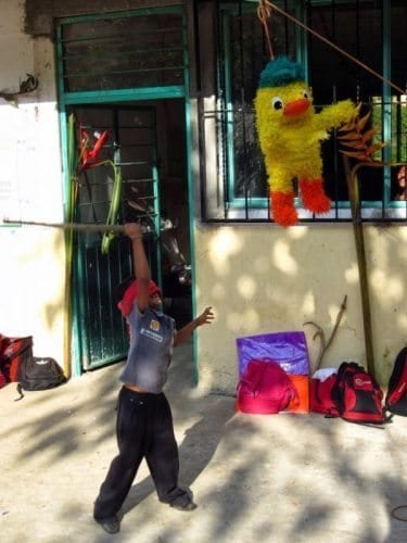 A child swinging at a paper mâché duck hoping for candy. 