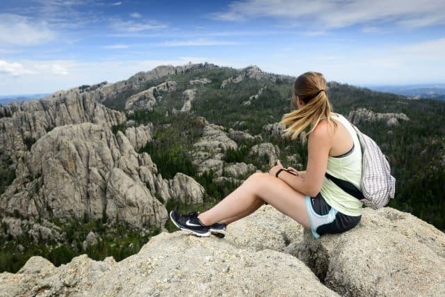 A hiker rests at the top of Harney Peak, the tallest peak in North America east of the Rockies. South Dakota Department of Tourism Photos.