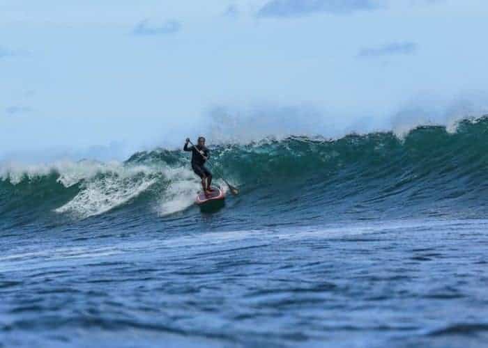 Titus Kinimaka slices across a wave face on his stand up paddleboard in Hanalei Bay Kauai HI. Photo by Ry Cowan