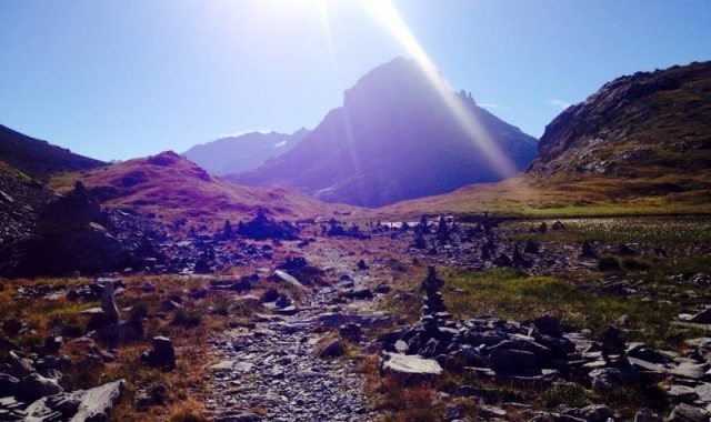 The sun shining out from behind the tremendous mountain.