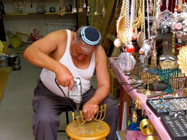 A metal Smith working on his goods at the market place in Tel Aviv. 