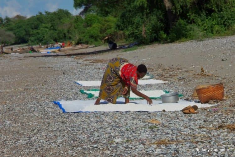 A woman spreads her cassava out to dry in the sun along the edge of Lake Malawi.