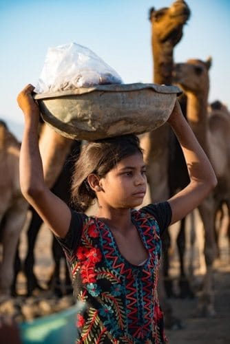 A young girl carrying food for the many vendors and locals who attend the fair.