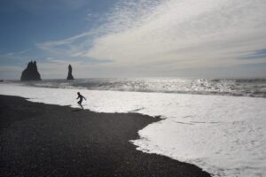 Iceland: Save Money By Camping A child races the waves at Dyrholaey, Iceland. Monica Schimanke photos.