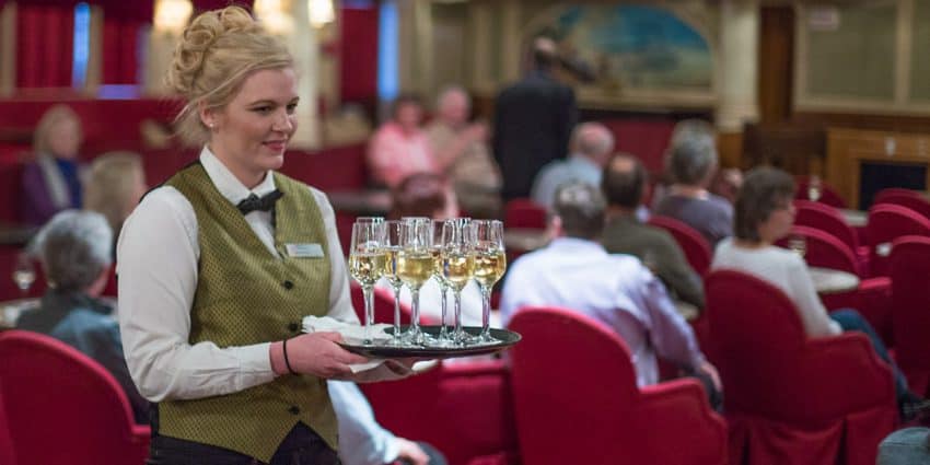 A crewmember of the American Queen steamboat in the dining quarters. Photo: American Steamboat Company | GoNOMAD Travel