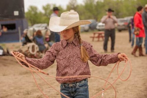 Harley Meged practices roping back behind the bucking chutes while her family is involved in helping to run the Bucking Horse Sale.