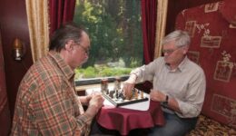 Two men playing chess as they ride the train to their next destination.