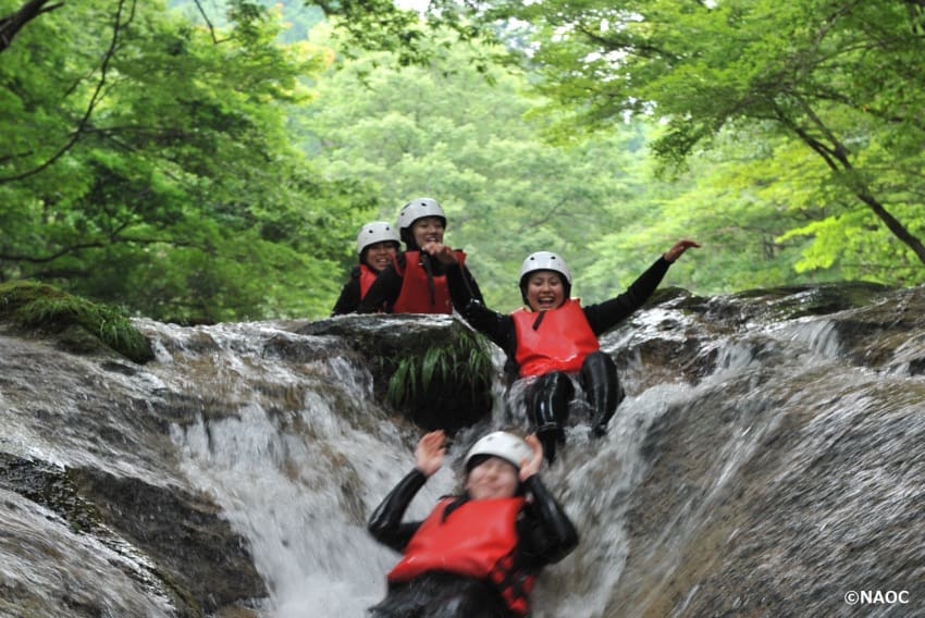 Some canyoners taking a plunge down a natural waterslide.