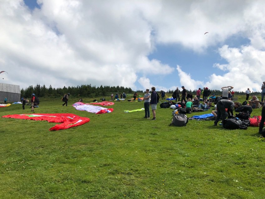 Paragliders line up to take off and soar from the top of Niedere, a tall peak in Bregenzerwald, Austria.