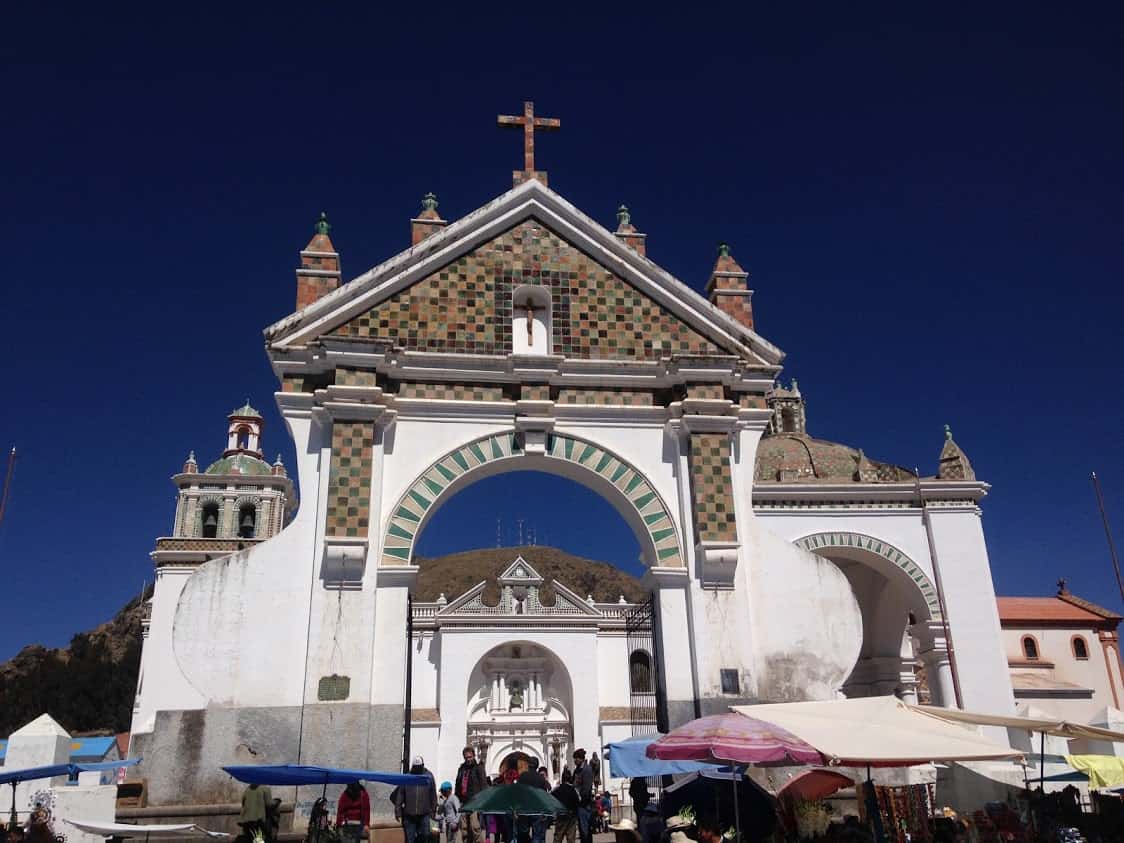 The Basilica de Copacabana glows between the blue sky and blue vendor umbrellas.