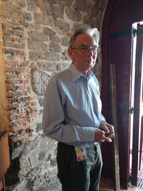 Koos Willemse is a volunteer guide at St. Nicholas Chapel, circa 1030. Some of the stones on the wall behind him are from Roman buildings dug up from surrounding grounds and used in the construction of the chapel.