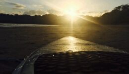 The setting sun glistens off of a surfboard in Panama.