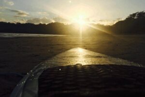 The setting sun glistens off of a surfboard in Panama.
