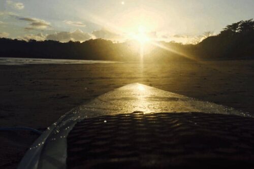 The setting sun glistens off of a surfboard in Panama.