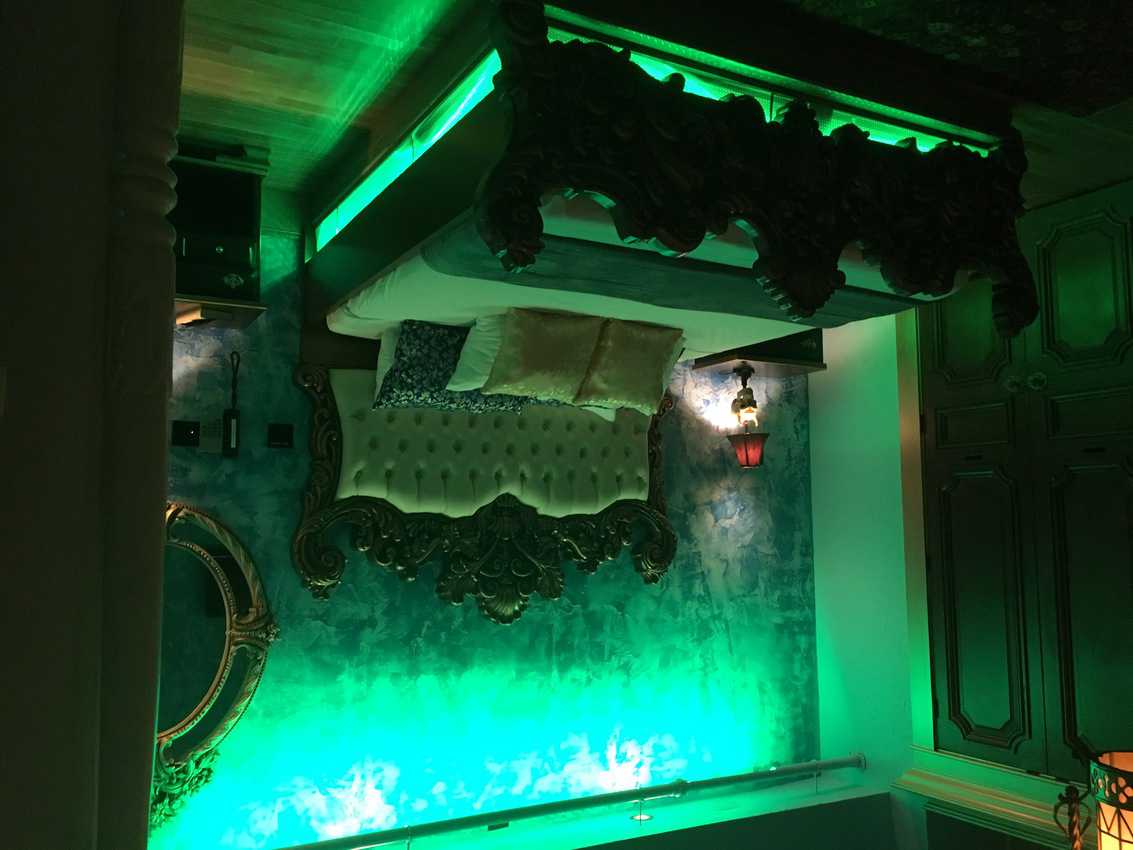 A glowing green master bedroom in the Haunted Castle Suite at Adventure Suites Hotel.