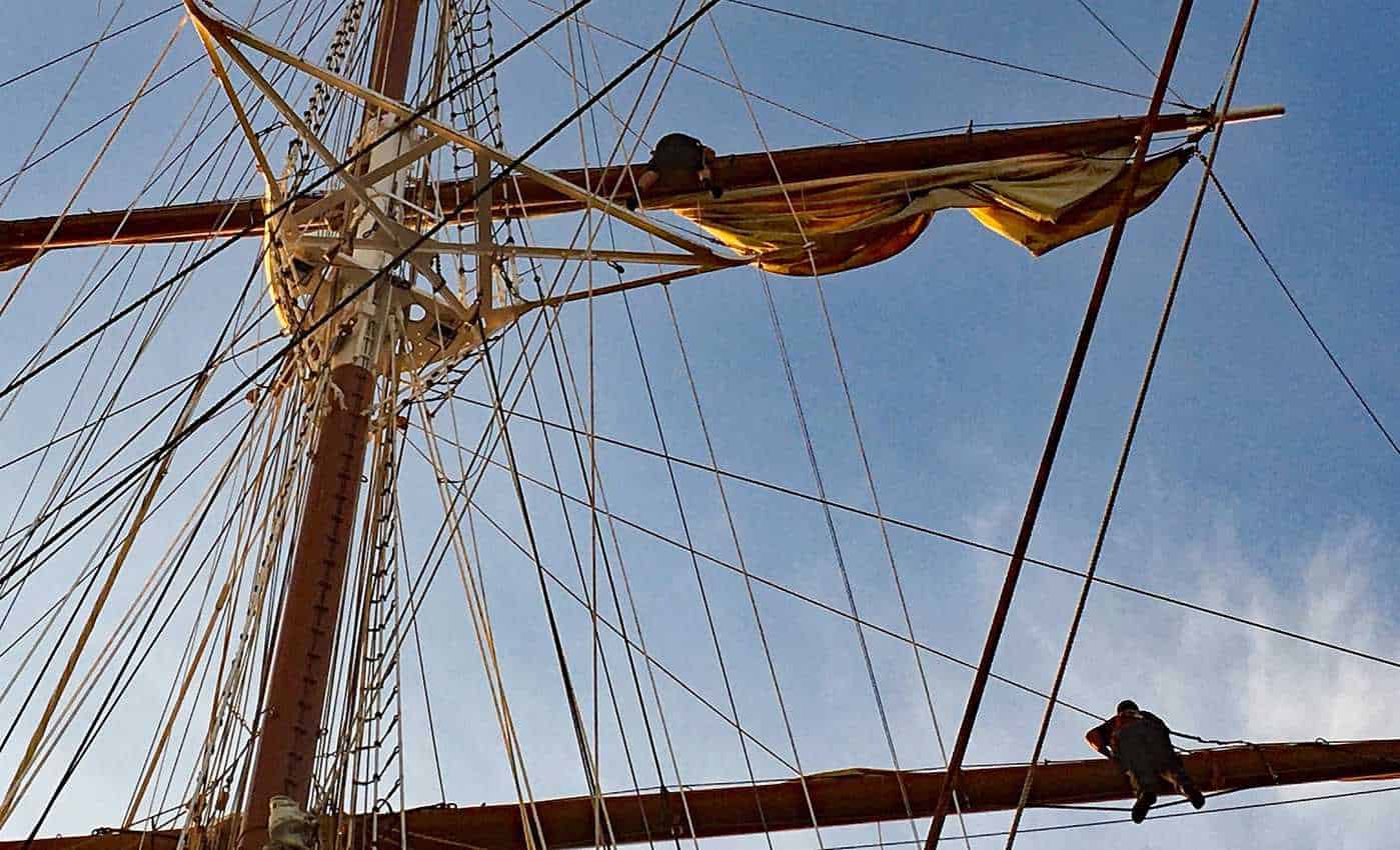 Eighteen deckhands on Sea Cloud balance on her riggings to set her sails by hand. 