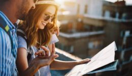 Multiethnic traveler couple using map together on sunny day