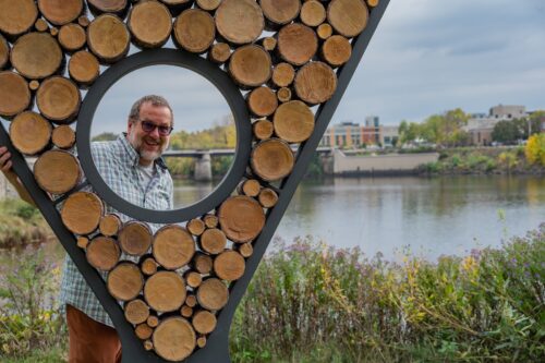 Artist Dan Ingersol poses with his sculpture, "Ingrain,." This People's Choice winner in 2020 is on permanent display in downtown Eau Claire.